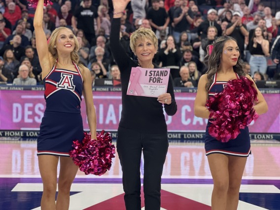 Ginny L Clements holding sign with UArizona cheerleaders