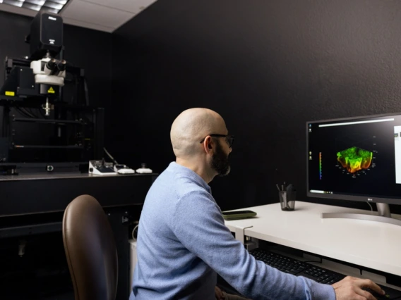 Researcher at computer operating a large microscope