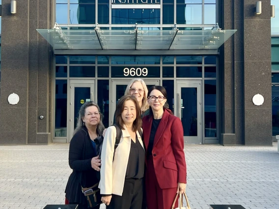 Four people stand in front of the National Cancer Institute.