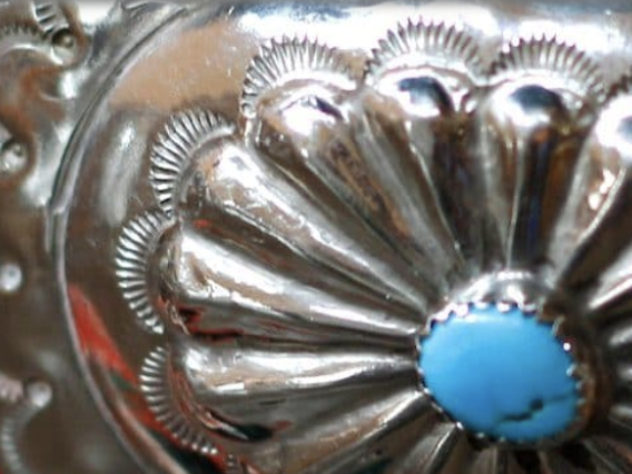 A closeup of a turquoise and silver buckle.