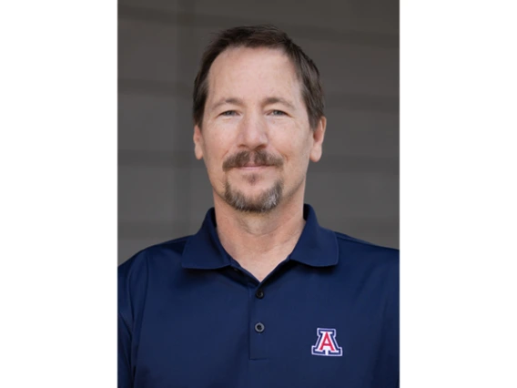 A portrait of Scott Carvajal wearing a blue polo shirt with a University of Arizona logo
