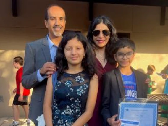 Dr. Rachna Shroff with husband and two children smiling for an outdoor photo..