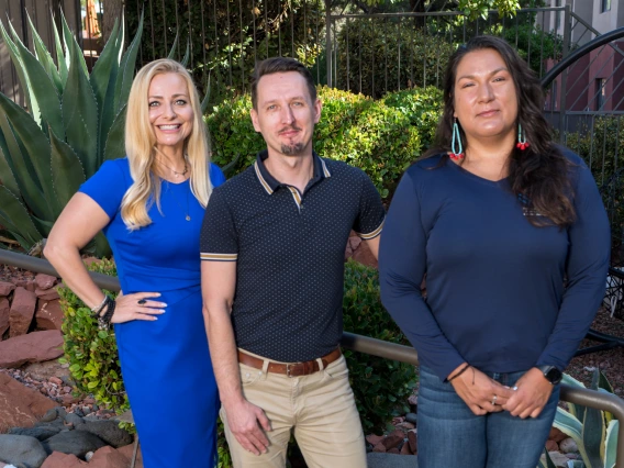 Three people stand for a group photo outdoors.