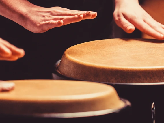 Two people play drums with their hands.