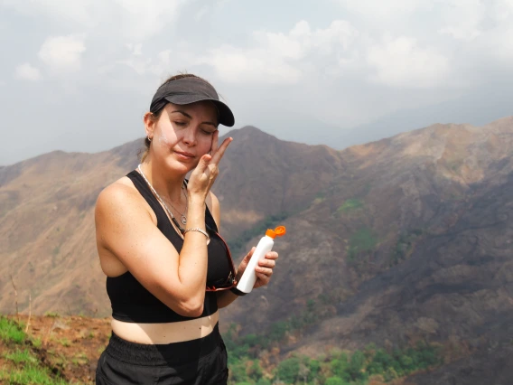 Person applying sunscreen on a hike.
