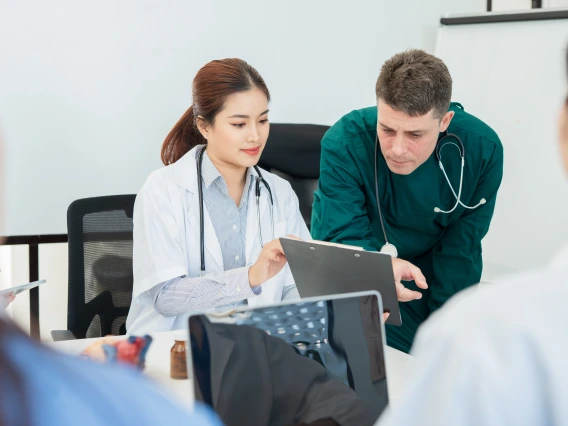 Two healthcare workers look at a computer.