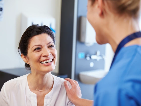 A caregiver has their had on a patient's shoulder.