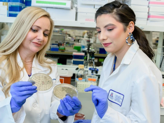 Two people examine a petri dish.