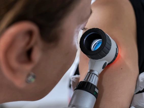 Dermatologists examines a patient's arm.