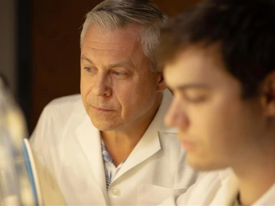 Gregory Rogers examines a lab sample with his student in the lab.