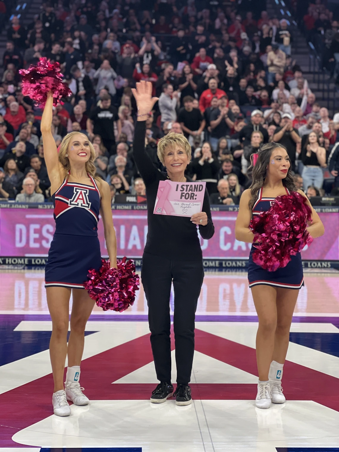 Ginny L Clements holding sign with UArizona cheerleaders