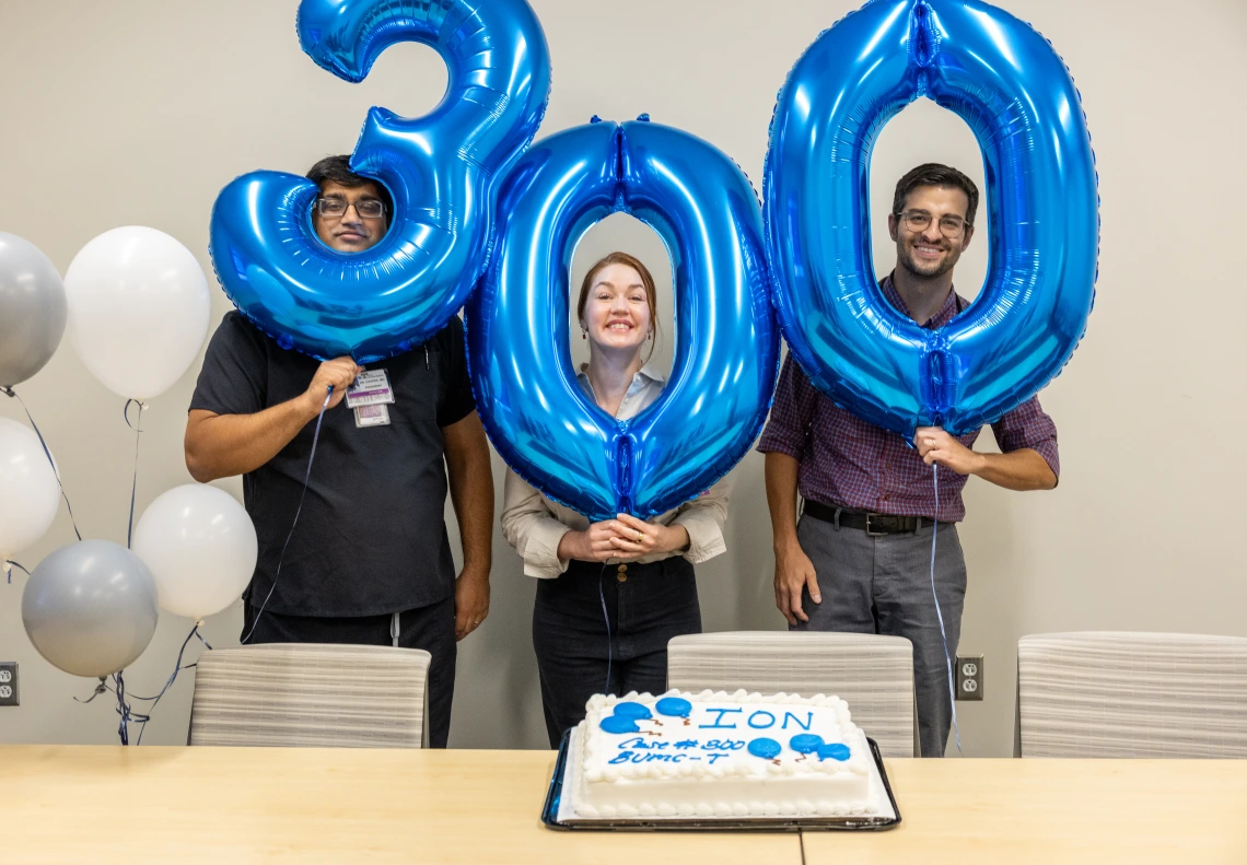 Three pulmonologists hold balloons celebrating 300 biopsies