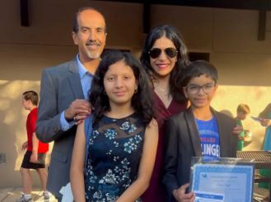 Dr. Rachna Shroff with husband and two children smiling for an outdoor photo..