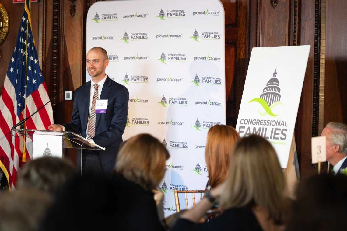 Person speaks at podium indoors in front of an audience. 