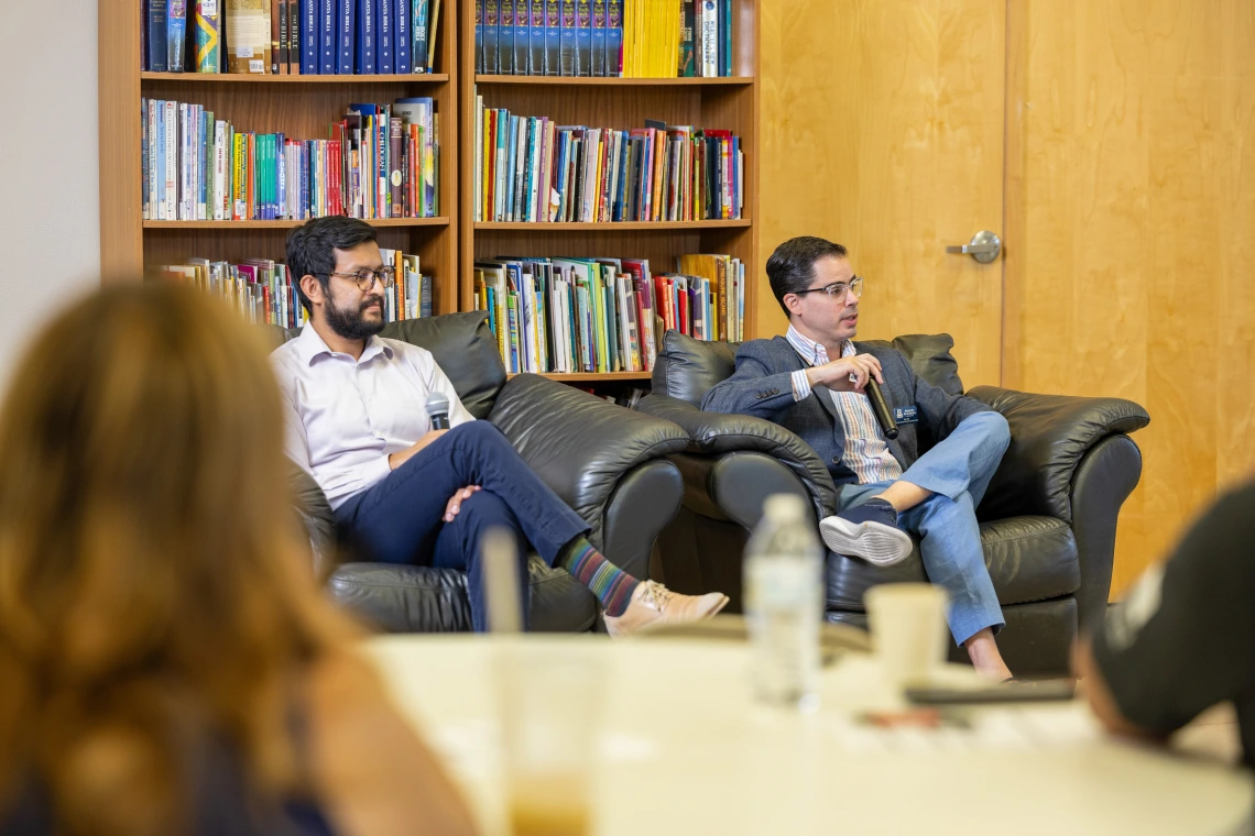 two people sit in chairs at a meeting.