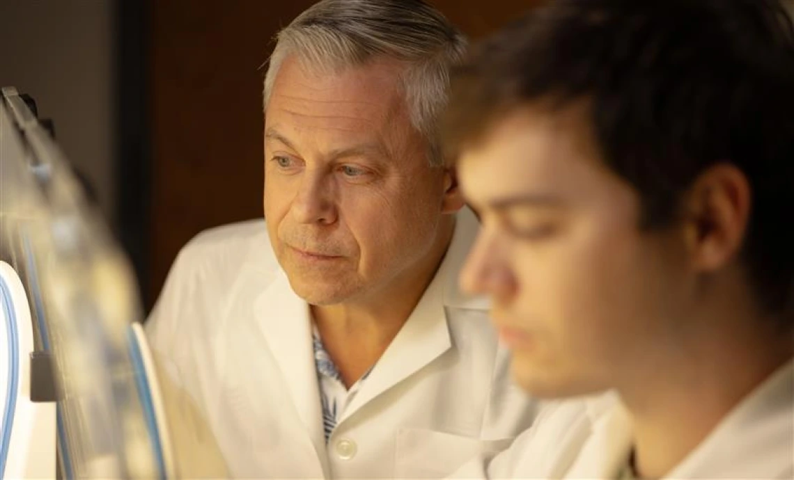 Gregory Rogers examines a lab sample with his student in the lab.