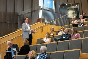 A man stands up and speaks in an auditorium.