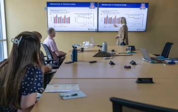 A person teaches a class to students sitting at a table.