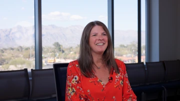 A person smiles for the camera in a meeting room at the University of Arizona Cancer Center.