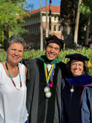 Jonathan Credo poses for a photo in his cap and gown with two mentors.