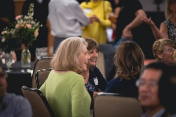 People enjoy conversations at several tables at the event dinner.