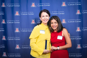 Dr. Clara Curiel and Dr. Rachna Shroff pose for a photo during the Awards Dinner. They are standing in front of a backdrop, and Dr. Curiel is holding an award.