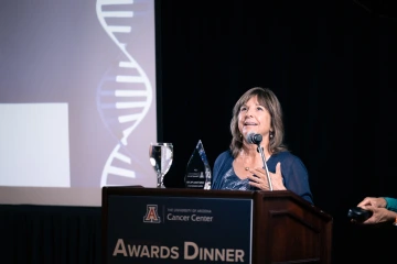 Cynthia Thomson speaks at a podium holding her Lifetime Achievement award