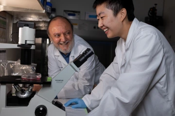 Professor Carlos Caulin laughs with student Manlin Shao in the Caulin Lab.