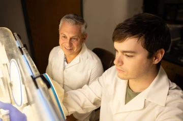 Professor Gregory Rogers watches student Matthew Coope as he examines specimens in the Rogers Lab. 