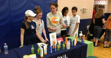 SASS students work at an information table at an indoor event.
