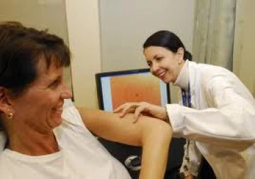Dr. Clara Curiel examines a patient's arm for skin cancer.