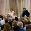 Three people sit around a table in front of an audience during the GLC Breast Cancer Research Symposium 