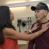 A doctor examines a patient in an examining room. The patient is wearing a Navy ball cap.