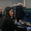 A student works on a computer in a lab at the cancer center with her mentor.