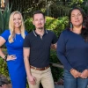 Three people stand for a group photo outdoors.