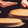 Two people play drums with their hands.