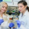 Two people examine a petri dish.