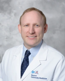 Daniel Goldberg smiles in a portrait while wearing a white lab coat.