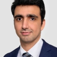 Photo of Faisal Jehan wearing a dark suit and tie.